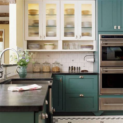 A Kitchen With Green Cabinets And Stainless Steel Ovens In The Center