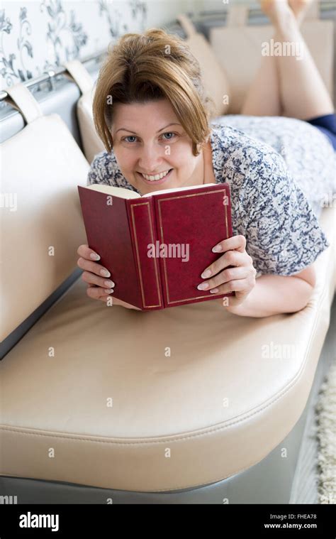 Woman Reading A Book Lying On Couch Stock Photo Alamy
