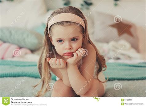Indoor Portrait Of Sad Cute 5 Years Old Child Girl Sitting On Bed Stock