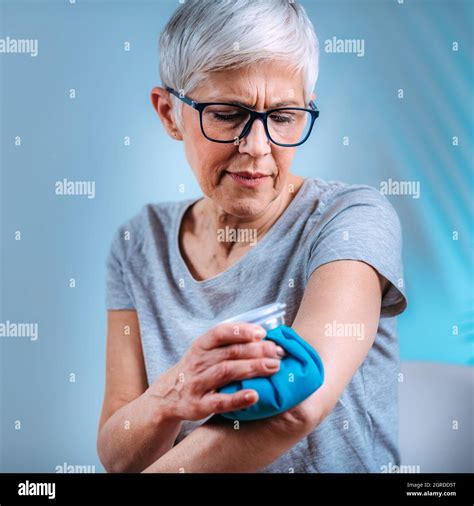 Elbow Pain Treatment Senior Woman Holding An Ice Bag Compress On A