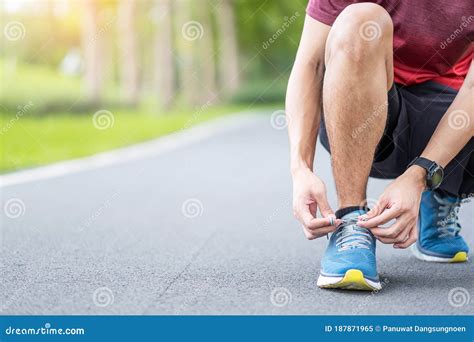 Young Adult Male In Sportswear And Smartwatch Tying Shoelace In The