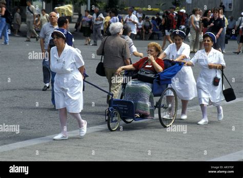 Nurses Wheeling A Disabled Person For The Grotto Blessing At Lourdes
