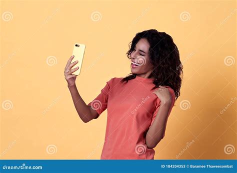 Portrait Of A Happy Young African Woman Selfie Celebrating With Mobile Phone Isolated Over