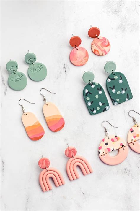 Six Pairs Of Colorful Earrings On A Marble Surface With White And Green