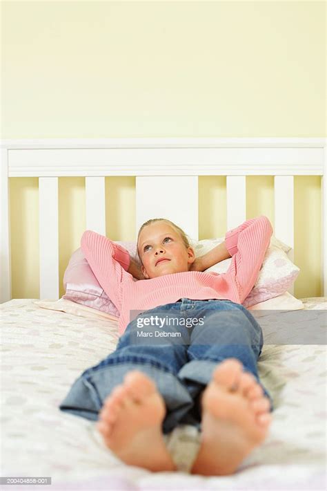 Girl Lying On Bed With Hands Behind Head Looking Up High Res Stock