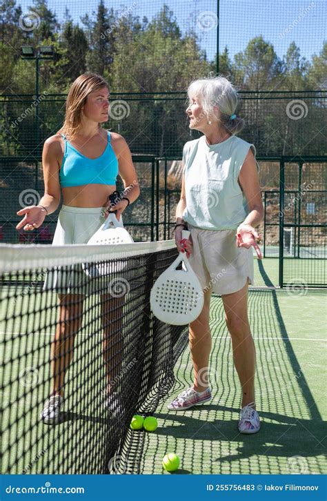 Two Women With Rackets In Their Hands Chatting After Playing Padel On