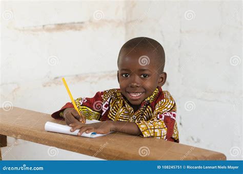 Laughing Little African School Boy Sitting In Desk Smiling At Ca Stock