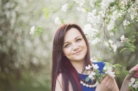 Beautiful Young Brunette Woman Standing Near The Blossoming Apple Tree On A Warm Spring Day