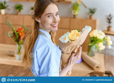 Beautiful Young Female Florist Holding Bouquet Of Tulips And Smiling At