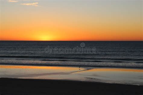 Beautiful Sunset Over Calm Ocean With Reflections On The Sandy Beach