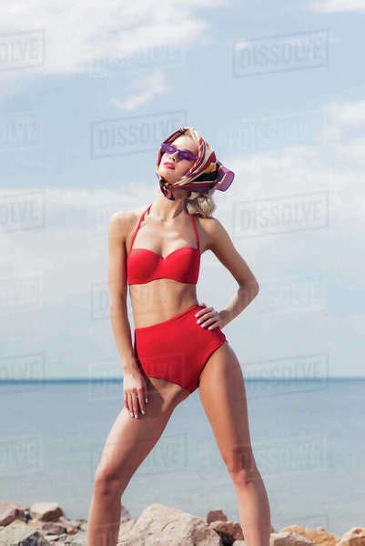 Stylish Elegant Girl Posing In Red Bikini Silk Scarf And Sunglasses On Rocky Beach Stock