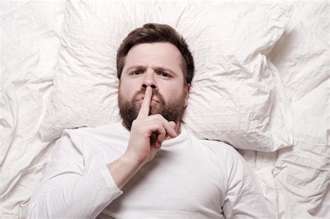 Premium Photo Serious Bearded Man Lying In Bed And Puts Index Finger