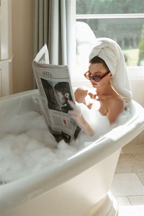 A Woman Sitting In A Bathtub Reading A Newspaper