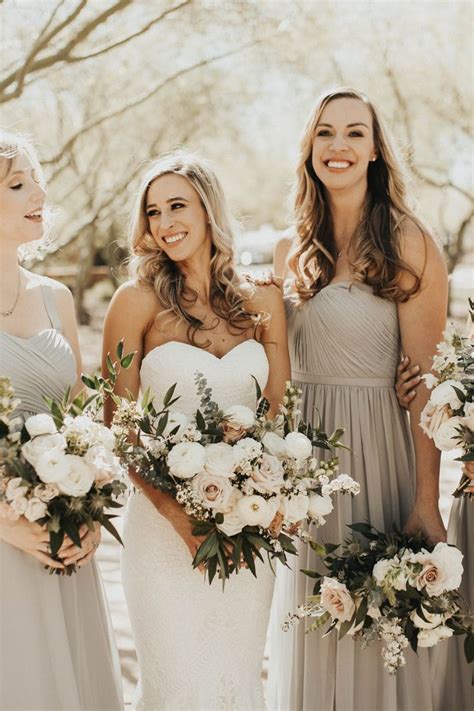 Three Bridesmaids In Grey Dresses Holding Bouquets