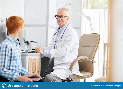Senior Doctor Talking To Teenage Boy Stock Photo Image Of Cheerful