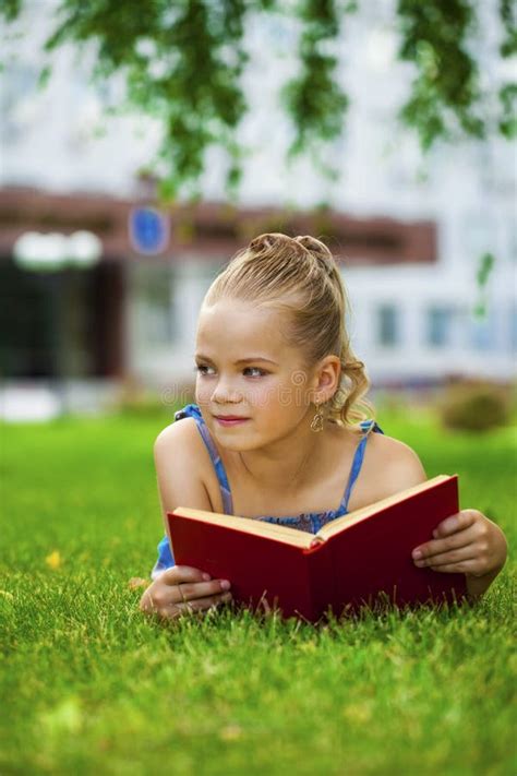 Adorable Cute Little Girl Reading Book Outside On Grass Stock Photo