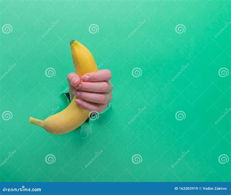 A Woman Holds A Banana In Her Hand Inserted Through A Hole In Torn