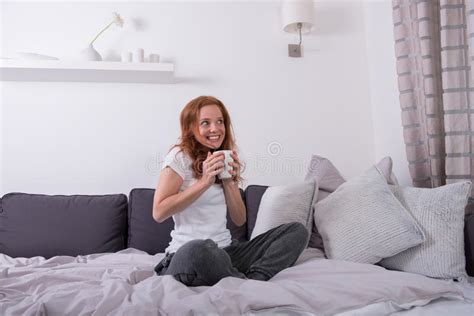 Young Woman Sitting On The Bed And Enjoying Her Coffee Stock Image