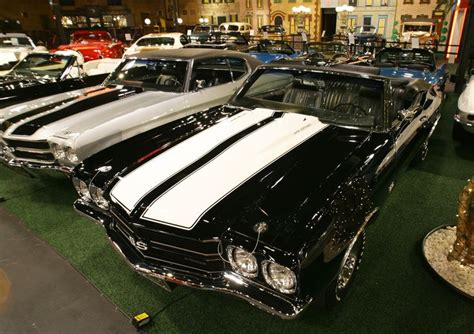 Several Classic Muscle Cars Are On Display In A Showroom With Green