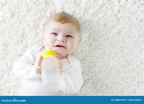 Cute Adorable Ewborn Baby Girl Holding Nursing Bottle And Drinking