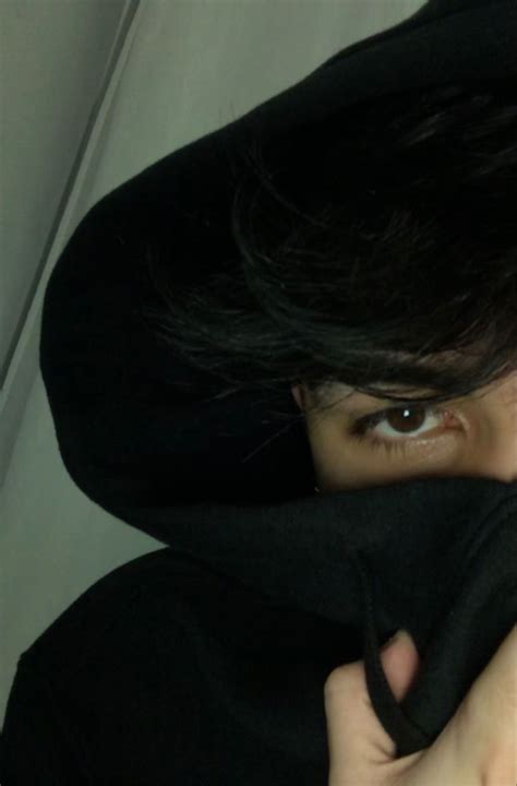 A Person Wearing A Black Hoodie And Covering Their Face With A Black