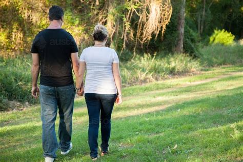 Image Of Couple Walking Away Through Park Holding Hands Austockphoto