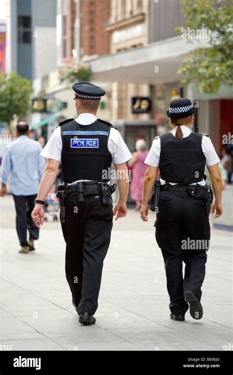 Back View Of Two Police Officers Male And Female Walking Down The High Street In Southend On
