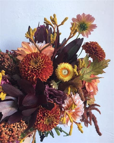 With cheery sunflowers nuzzled into a bunch of orange and coral roses, alstroemeria and purple statice in a tall vase, this striking flower arrangement captures the essence of a sunflower's sunny appearance. Beautiful fall bouquet. Burnt orange, yellow and plum ...