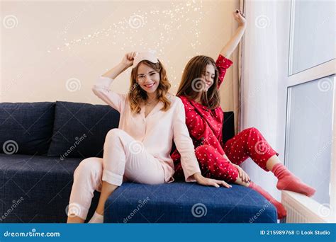 Cute Girl In Red Pajamas Sitting On Sofa Near Window Photo Of Joyful Caucasian Ladies Relaxing