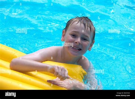 Happy Young Boy Relaxing At The Swimming Pool On A Yellow Lilo Stock