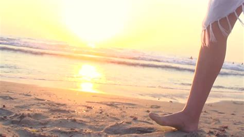 Legs Of Beauty Girl Walking Barefoot Along Wet Sand Beach Over Sunset