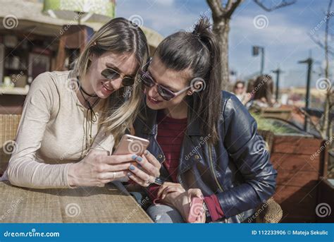 Two Beautiful Young Women Having Fun Outdoors While Using Their