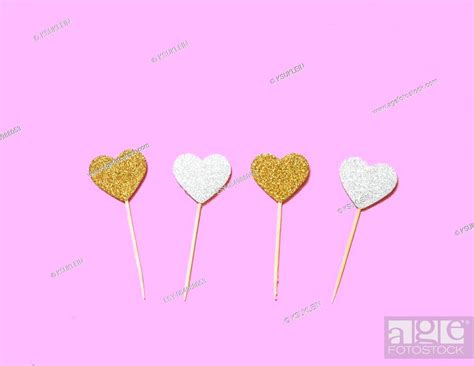 Gold And Silver Glittering Heart Shaped Cake Toppers On Pink Background