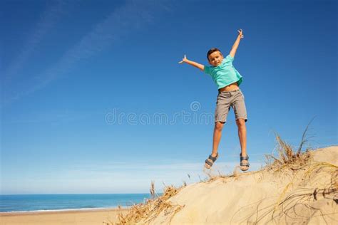 Cute Boy Jump On The Sand Dune Beach Raising Hands Stock Image Image