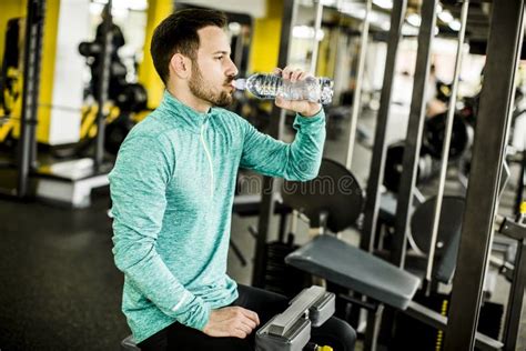 Portrait Of Young Handsome Man Drinking Water In A Gym Stock Photo