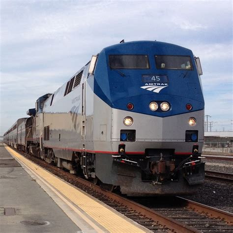 A Blue And Silver Train Traveling Down Tracks Next To A Loading