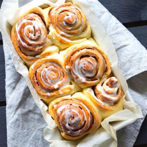 Several Cinnamon Rolls Sitting On Top Of A Piece Of Parchment Paper