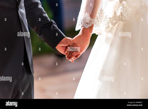 Young Married Couple Holding Hands On Ceremony Wedding Day Stock Photo