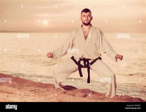 Young Man Is Training The Shiko Dachi Stance On The Beach Near The Sea