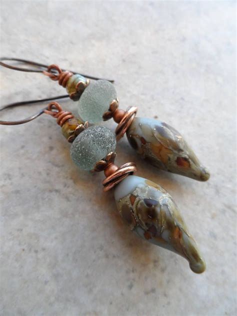 Three Glass Beads And Copper Wire Hang From Earwires On A Marble Table Top