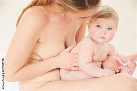 Naked mother bonding with naked baby on lap ภาพถายสตอก Adobe Stock