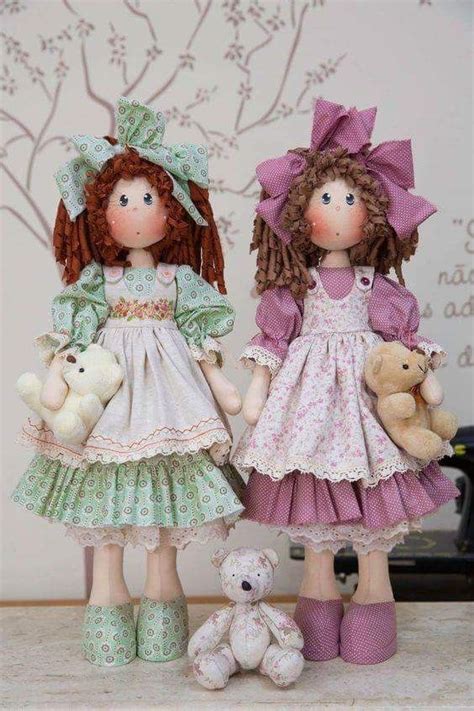 Two Dolls Standing Next To Each Other Holding Teddy Bears