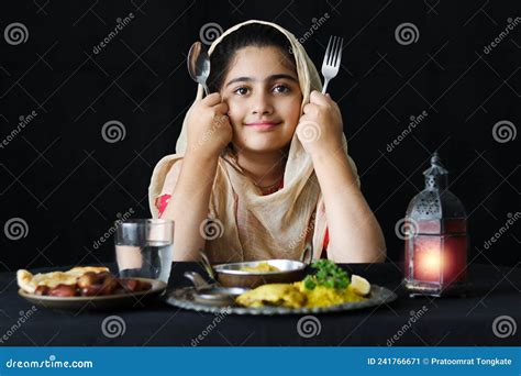 Adorable Smiling Pakistani Muslim Girl With Beautiful Eyes Sitting At Kitchen Table Holding