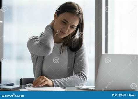 Unhealthy Young Woman Sitting At Workplace Rubbing Neck Feeling Pain