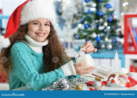 Happy Girl In Santa Hat Sitting With Christmas Present Stock Photo