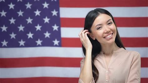 positive asian woman standing against usa flag background independence day stock footage