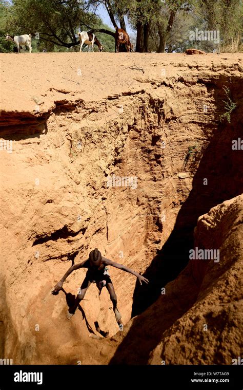 Himba Boy Coming Out Of A Deep Hole Dug Into A Dry River Bed To Access