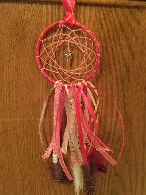 A Pink And White Dream Catcher Hanging On A Wall