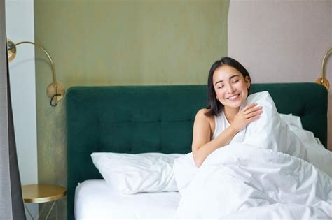 Счастливая кореянка просыпается в своем гостиничном номере лежа в