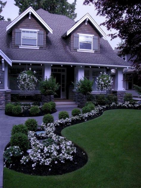 A House With Lots Of Flowers In The Front Yard And Landscaping On The